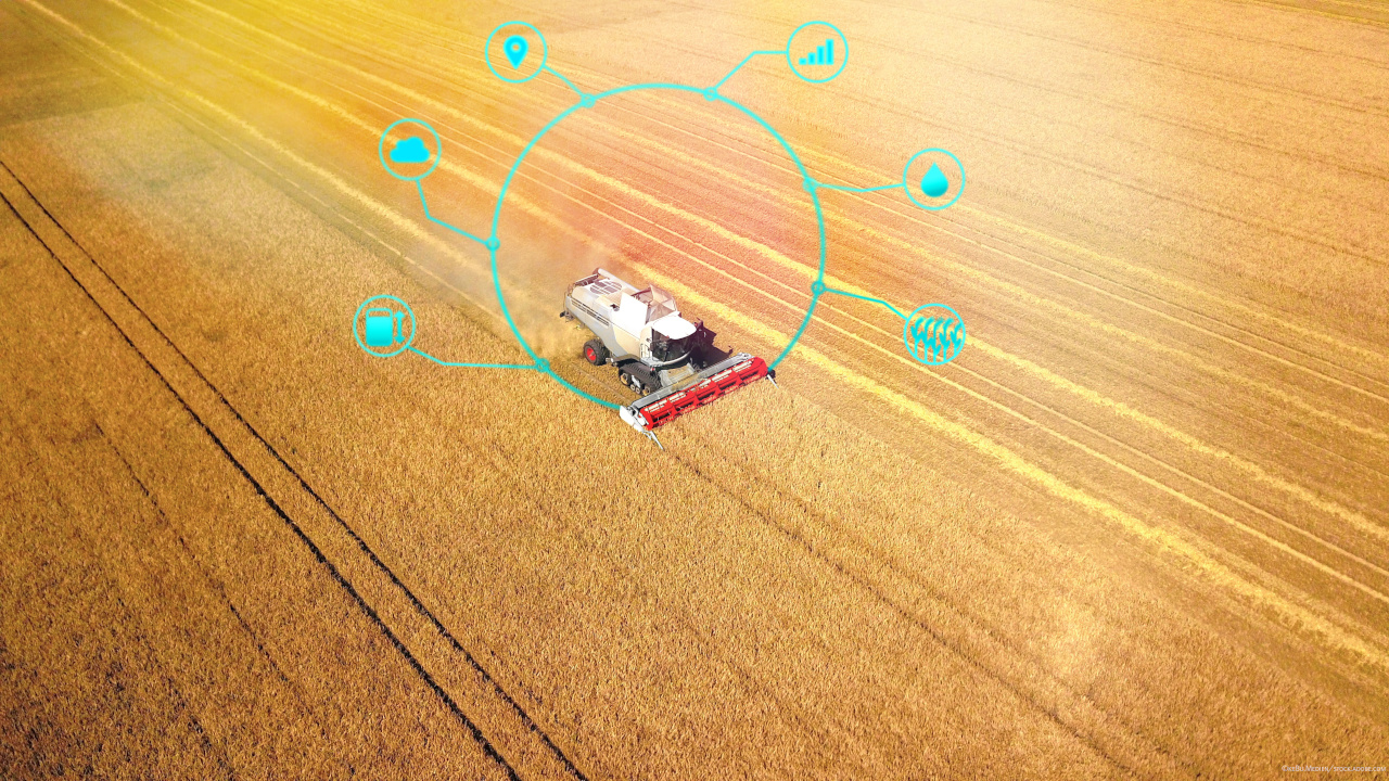 Mähdrescher auf einem gelben Getreidefeld umgeben von digitalen Symbolen