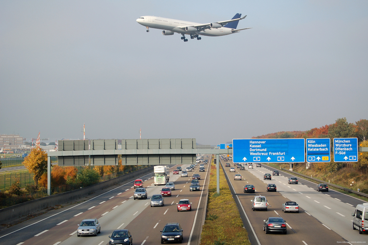 Ein Flugzeug fliegt über eine Autobahn